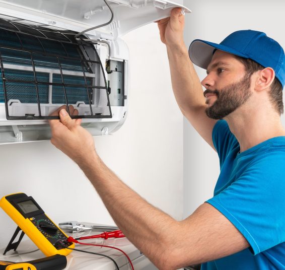 Installation service fix  repair maintenance of an air conditioner indoor unit, by cryogenist technican worker checking the air filter in blue shirt and baseball cap